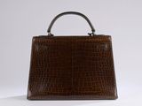 the brown crocodile skin handbag is sitting on a white surface