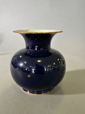 un vase bleu à bord doré posé sur une table