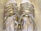 silver sandals with gold straps on a wooden floor