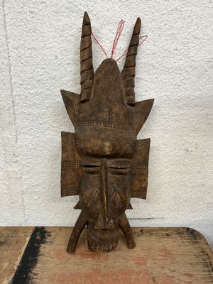an old wooden mask sitting on top of a piece of wood