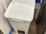 a white trash can sitting in the corner of a kitchen
