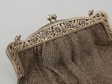 an antique silver purse with a chain handle and a flower design