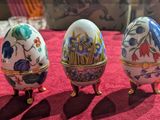 trois œufs décorés posés sur une nappe rouge