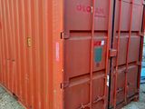 un conteneur d'expédition rouge posé au bord de la route