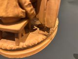 a statue of a man sitting on a stool next to a statue of a woman