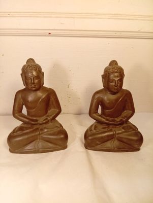 deux statues de bouddhas assis sur un socle blanc