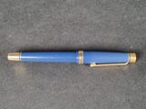a close up of a blue fountain pen on a gray surface