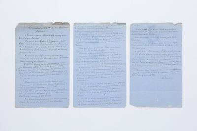 trois feuilles de papier bleu comportant des inscriptions, posées sur une surface blanche