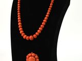 collier de perles orange orné d'un pendentif en forme de fleur, porté par un mannequin noir