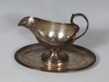 a silver gravy on a silver plate on a white table