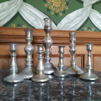 cinq bougeoirs en argent posés sur une table en marbre