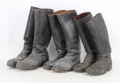 three pairs of old boots are lined up against a white background