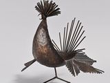 sculpture of a bird with feathers on a stand on a white surface