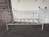 un banc en fer blanc posé à même le sol devant un mur blanc