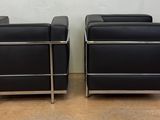 pair of black leather lounge chairs with chrome legs