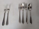 five forks and two spoons on a white table