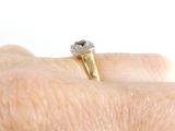 a person ' s hand holding a gold ring with a blue stone