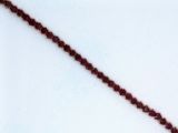 a red beaded necklace on a white surface