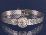 a silver bracelet with a clock on it on a table