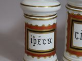 two white and gold jars with black writing on them