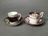 two cups and saucers are sitting side by side on a table