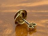 a pair of gold earrings sitting on a wooden table