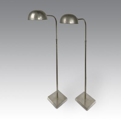 a pair of metal floor lamps on stands with a white background