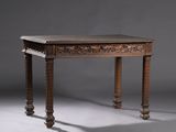 une vieille table en bois dont le plateau et les pieds sont sculptés