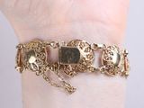 bracelet with a gold chain and charms on a woman ' s wrist