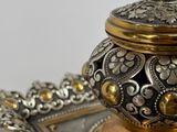 an ornate silver and gold plate with a lid on it