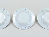 three white plates with designs on them sit on a white surface