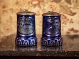 deux vases bleus posés sur une table, avec un papier peint à motifs floraux en arrière-plan