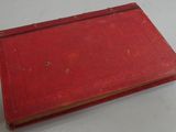 an old red book sitting on top of a white table