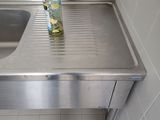 stainless steel sink in a public restroom with a bottle of alcohol on the counter