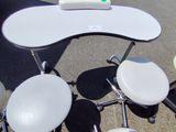 une table blanche et quatre tabourets posés à même le sol