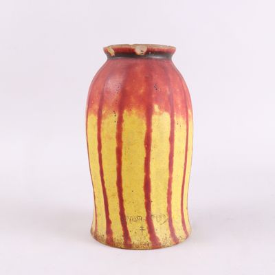 un vase rouge et jaune posé sur une surface blanche