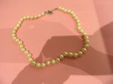 a pearl necklace on a pink surface with a shadow of a person