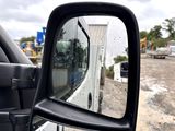a side view mirror of a truck parked on the side of the road