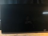 the flat screen tv is sitting on a wooden table next to a lamp