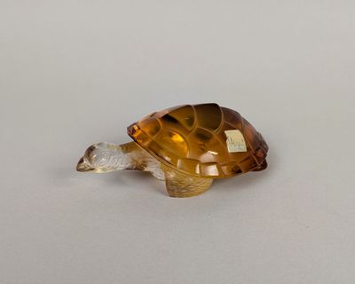 une petite tortue en verre posée sur une table
