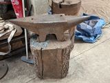 une vieille enclume posée sur une table, à côté d'un tas de vieux outils