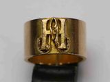un gros plan d'une bague en or sur laquelle figure la lettre h