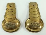 pair of brass candles with crowns on them on a white surface