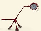 une lampe rouge posée sur des roulettes, sur une surface blanche