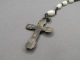 rosary necklace with a cross and white pearls on a gray background