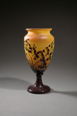yellow and brown vase sitting on top of a wooden stand