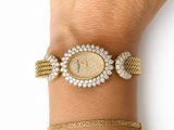 an image of a woman ' s wrist with a gold and diamond watch