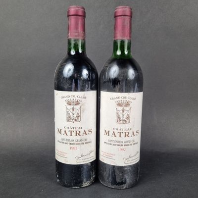 two bottles of red wine sitting next to each other on a table