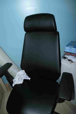 une chaise de bureau noire avec une assise noire, près d'un mur bleu