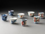 six petites tasses décorées sont posées sur une table
